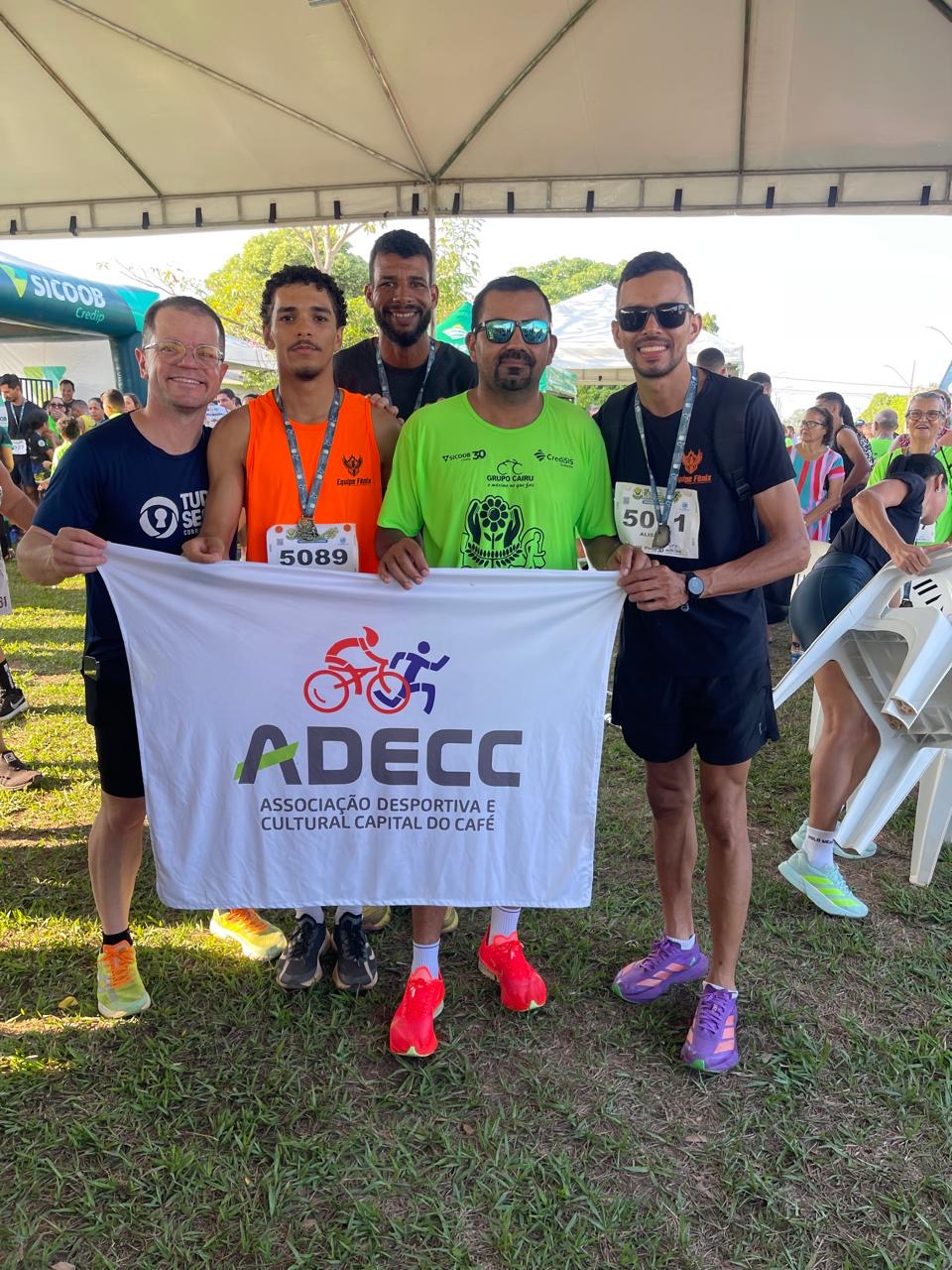 Equipe ADECC reunida sob tenda em evento esportivo